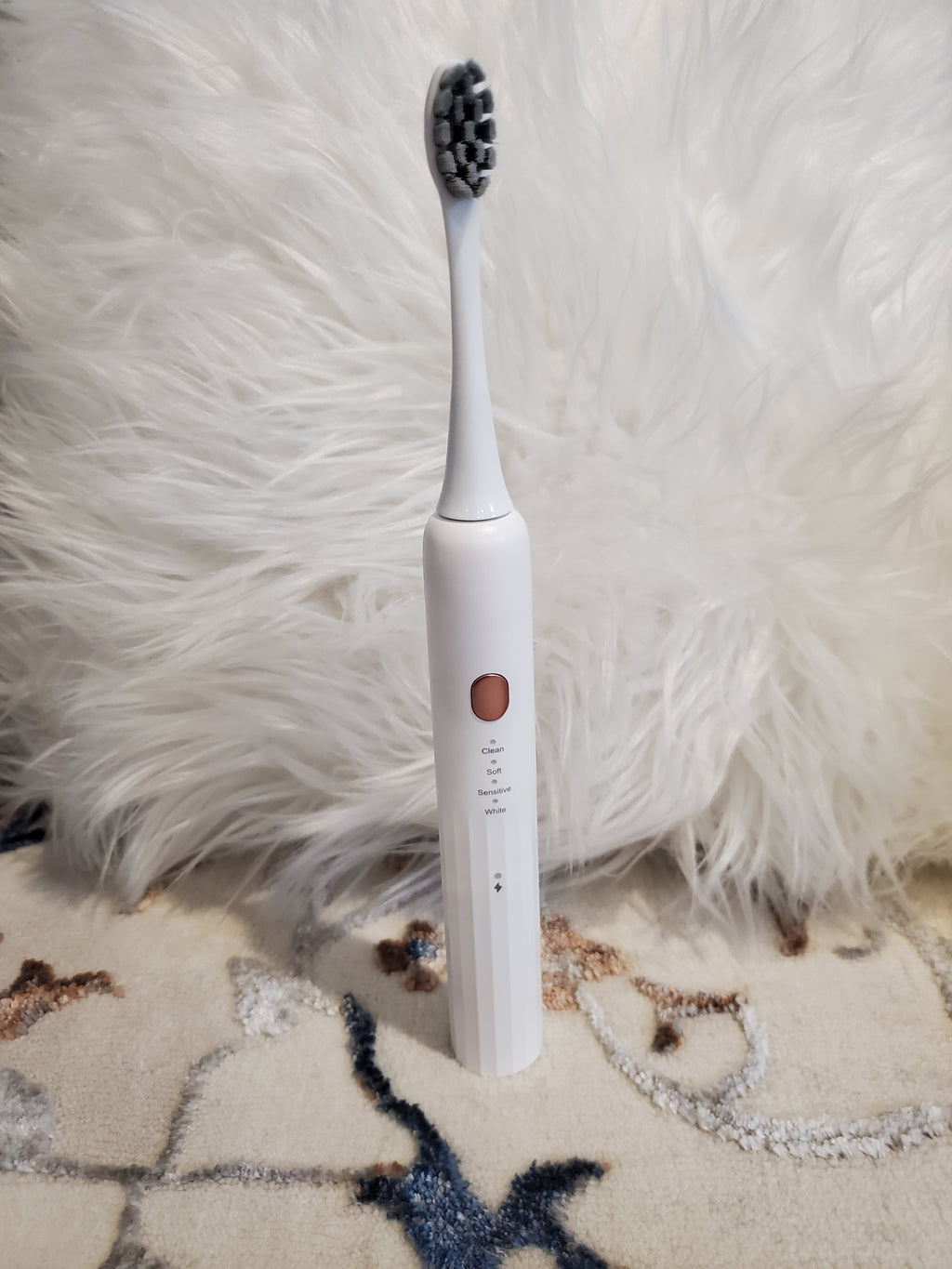 White electric toothbrush with bristles on a fluffy white surface