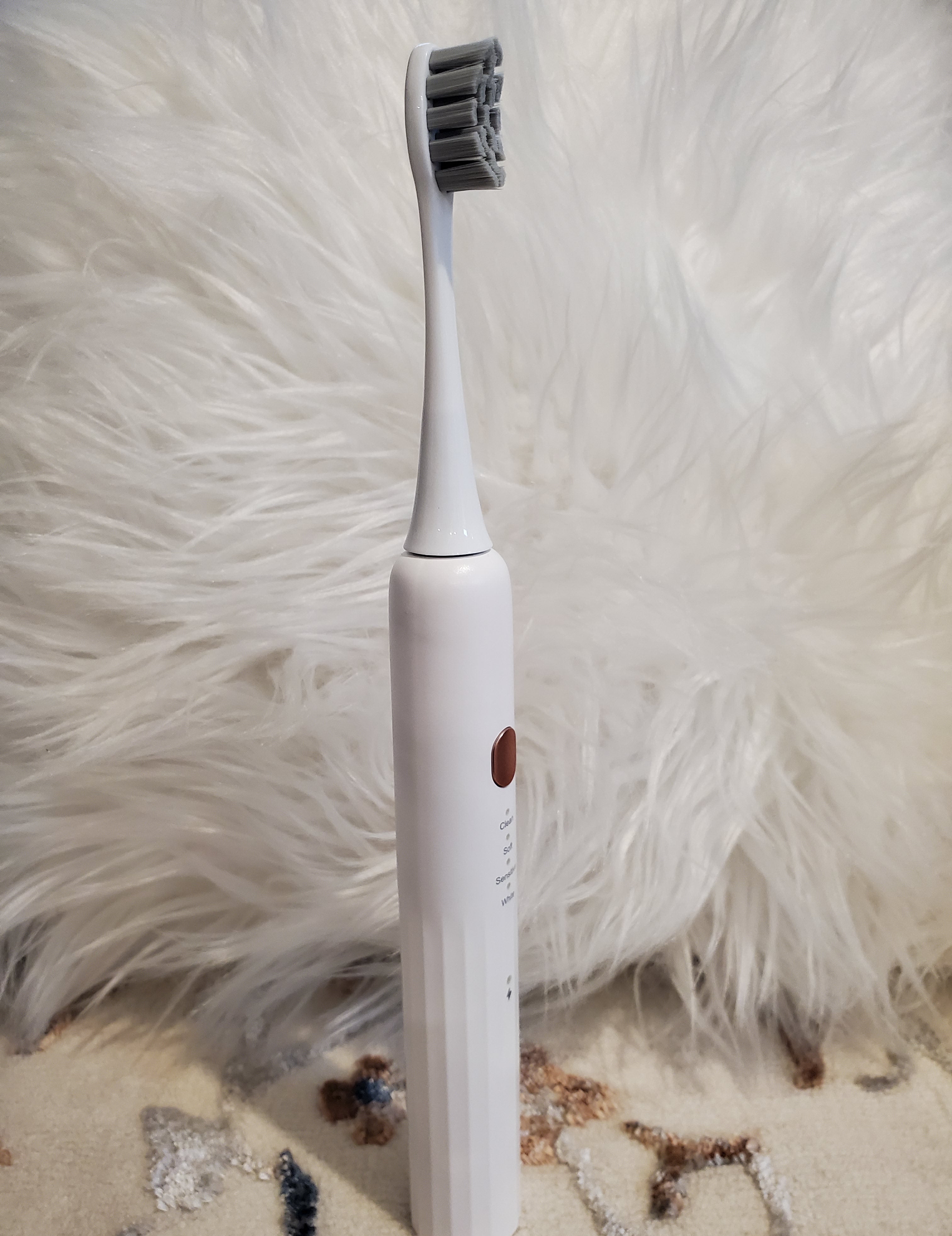 White electric toothbrush on a textured surface with a soft head brush