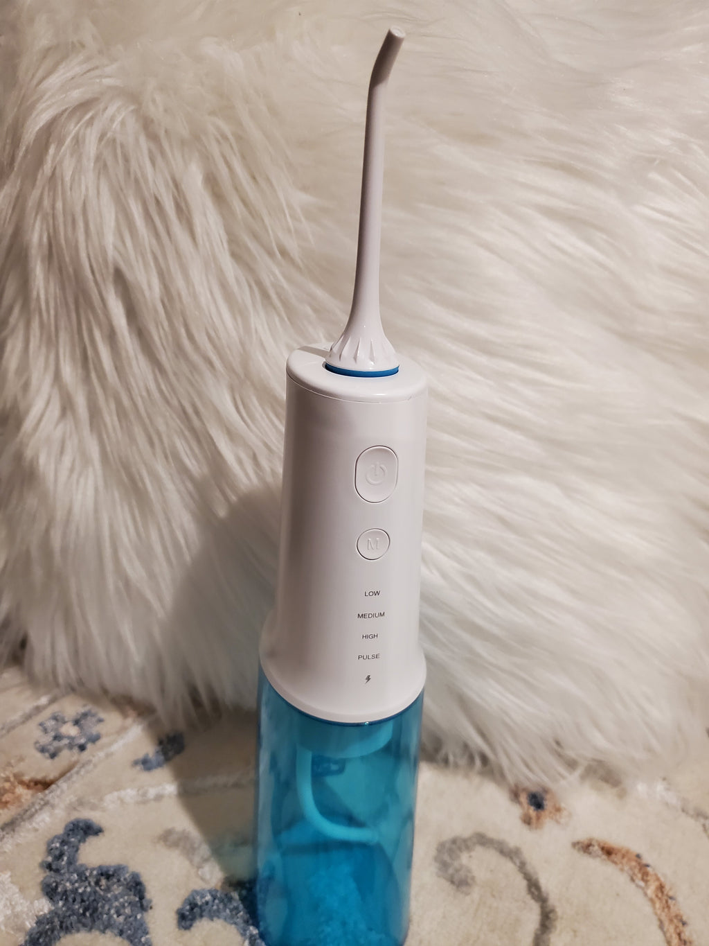 White and blue dental water flosser on a textured surface