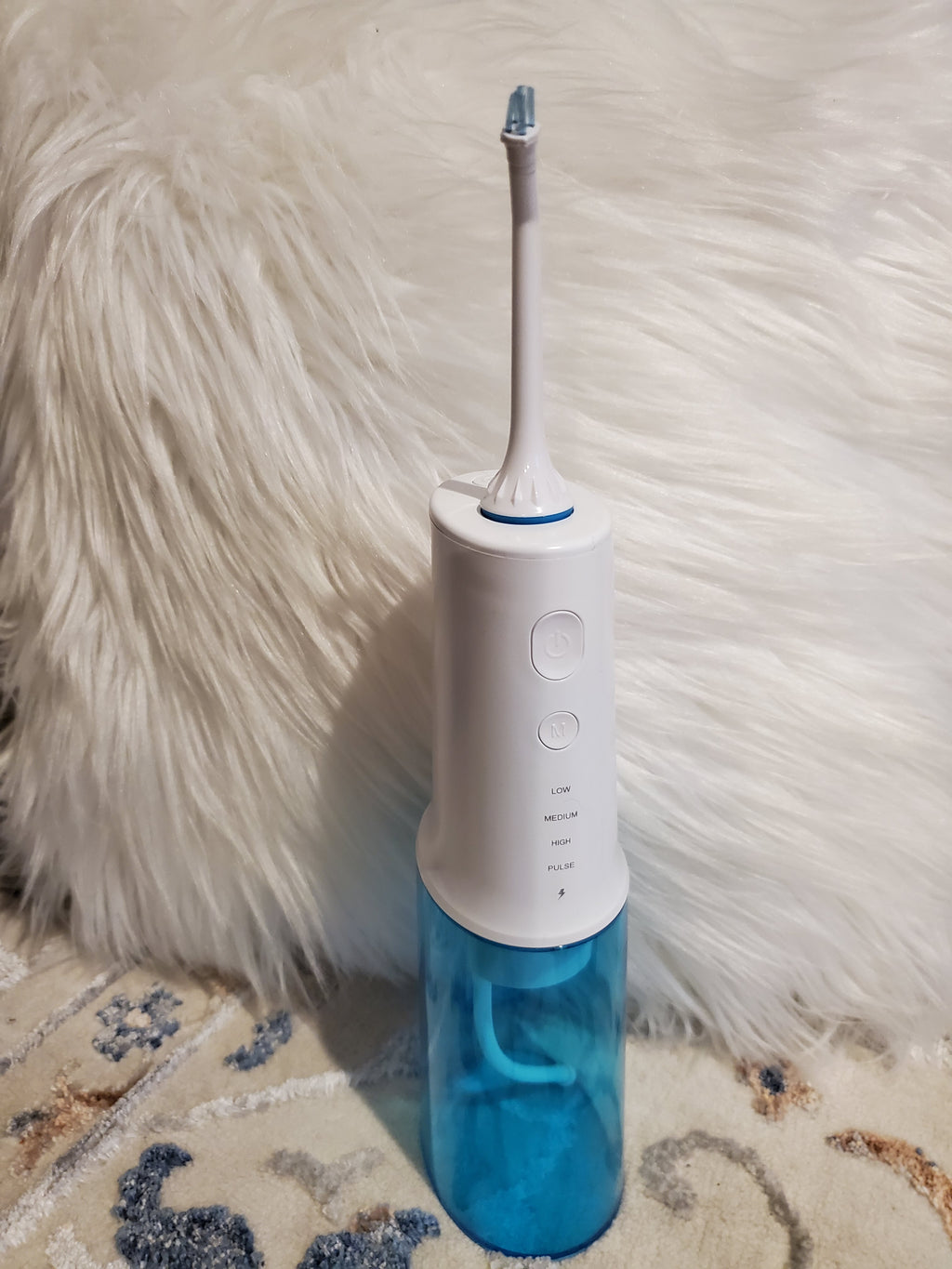 White and blue dental water flosser on a textured surface